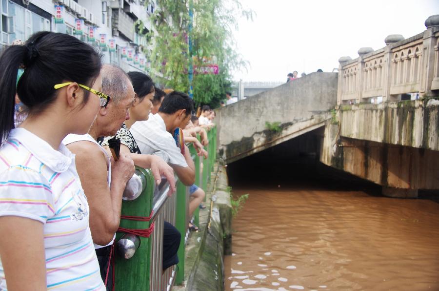 Local residents watch flood on Binhe Road in Quxian County of Dazhou City, southwest China's Sichuan Province, July 20, 2013. Due to sustained heavy rainfall, this year's highest flood peak of the Qujiang River which runs through northeast Sichuan and west Chongqing, a southwest China's municipality near Sichuan, passed Quxian County Saturday. More than one third of the downtown area of Quxian County was flooded. (Xinhua/Yu Junhua)