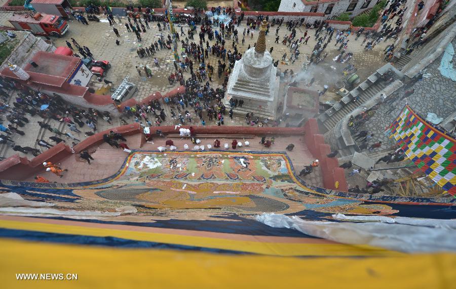 Devotees worship a huge Buddha portrait after unfolding it during the annual religious ritual in the Gandan Temple in Lhasa, capital of southwest China's Tibet Autonomous Region, July 22, 2013. Founded in 1409 by followers of Zong Kaba, founder of the Yellow Sect of Tibetan Buddhism, the Gandan Temple is the oldest among lamaseries of the Yellow Sect. (Xinhua/Purbu Zhaxi)