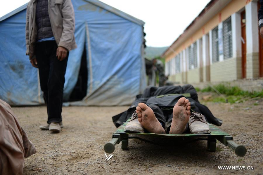 An injured villager lying on a stretcher waits for treatment in the quake-hit Yongxing Village, Meichuan Township, Minxian County, northwest China's Gansu Province, July 23, 2013. An emergency team of health workers sent by a military hospital in Gansu arrived in Minxian after a 6.6-magnitude earthquake jolted the province on Monday. They have received some 60 severely wounded people. (Xinhua/Jin Liangkuai)