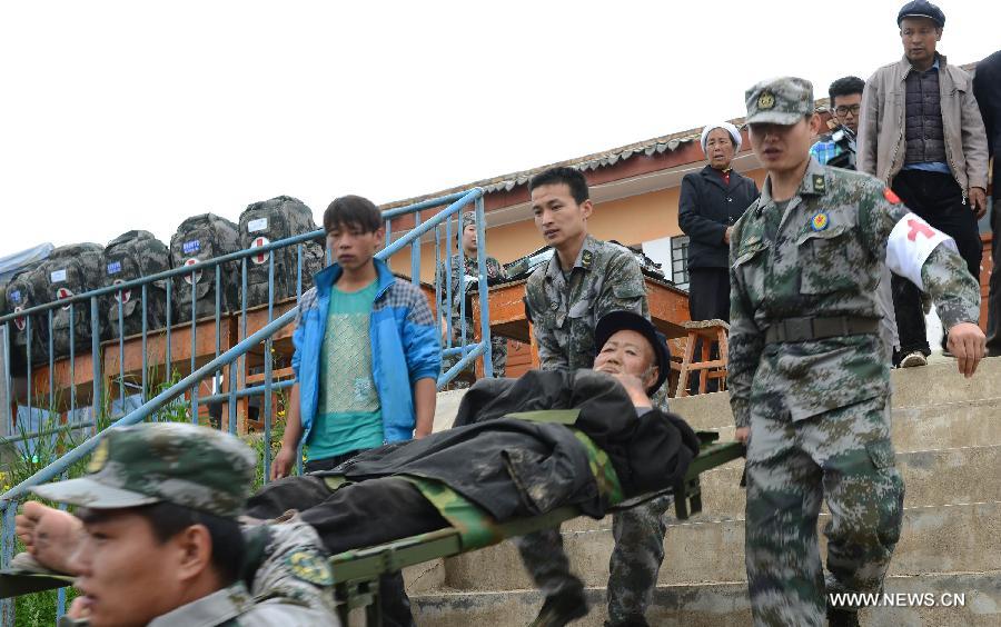 An ill villager is carried by military health workers in the quake-hit Yongxing Village, Meichuan Township, Minxian County, northwest China's Gansu Province, July 23, 2013. An emergency team of health workers sent by a military hospital in Gansu arrived in Minxian after a 6.6-magnitude earthquake jolted the province on Monday. They have received some 60 severely wounded people. (Xinhua/Jin Liangkuai)