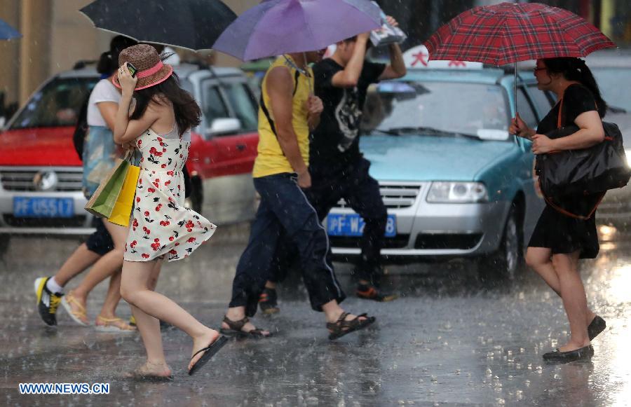 Residents walk in rain on Nanjing Road, east China's Shanghai, July 26, 2013. A rainstorm hit Shanghai Friday afternoon, bringing coolness to the scorching weather. (Xinhua/Yang Shichao)