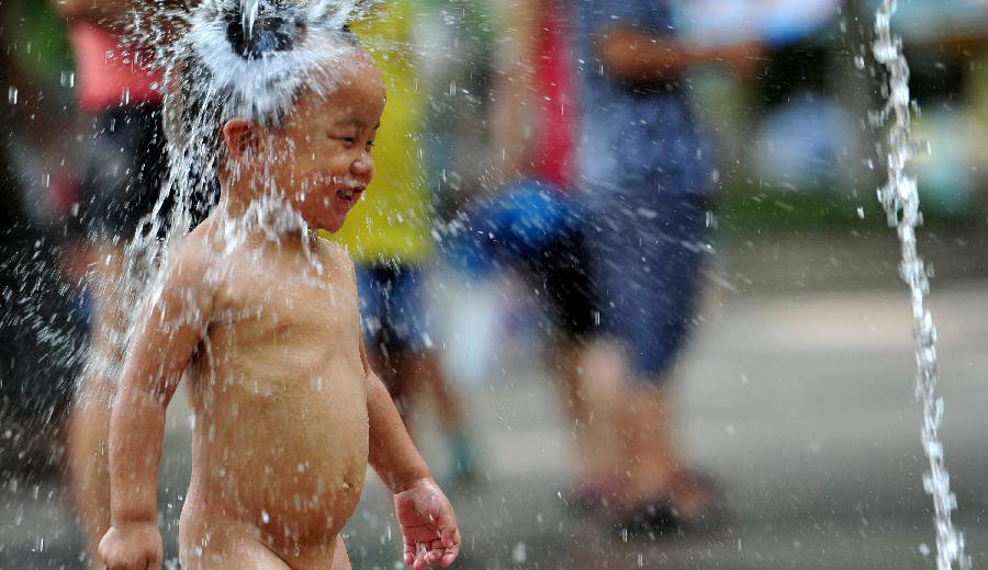 A young boy cools off in a fountain in Hangzhou City, capital of east China's Zhejiang Province, July 28, 2013. A heat wave hit many parts of the country these days. (Xinhua/Xu Hui)