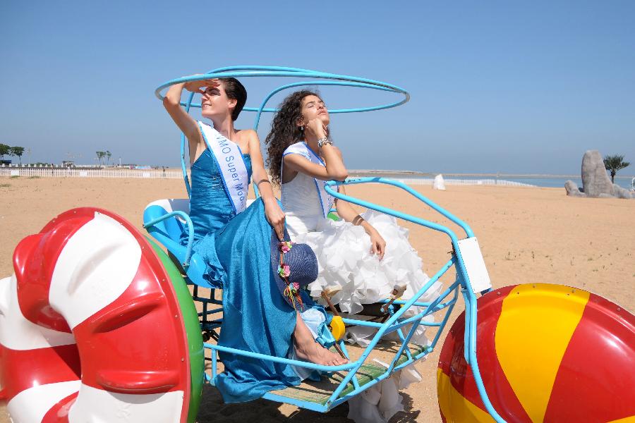 Contestants of the 23rd World Model Organization (WMO) world super model contest finals pose for pictures during a themed photography activity at the Dongjiang shore in north China's Tianjin Municipality, July 28, 2013. In total 37 super models from more than 20 countries and regions all over the world will compete during the final of the 23rd WMO super model contest on Aug. 2, 2013 in Tianjin. (Xinhua/Xue Liqiang)