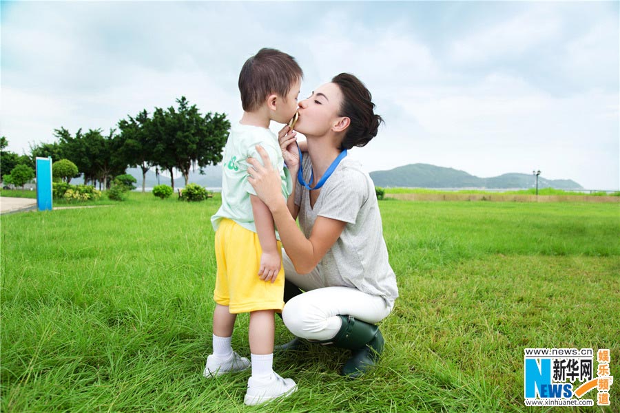 Chinese actress Cecilia Cheung poses for photos of an advertisement with a cute boy. (Photo/Xinhua)